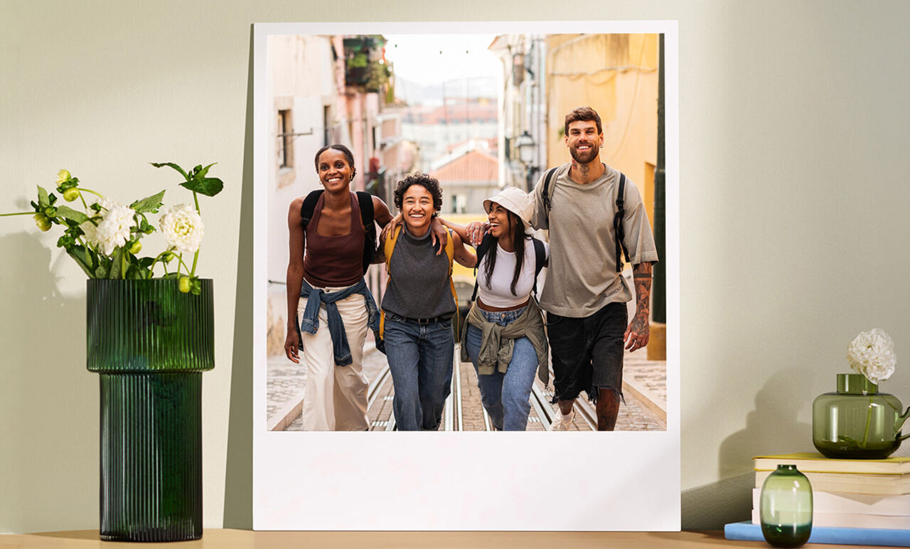 Póster fotográfico de un grupo de amigos paseando por una calle, expuesto sobre un mueble decorado.