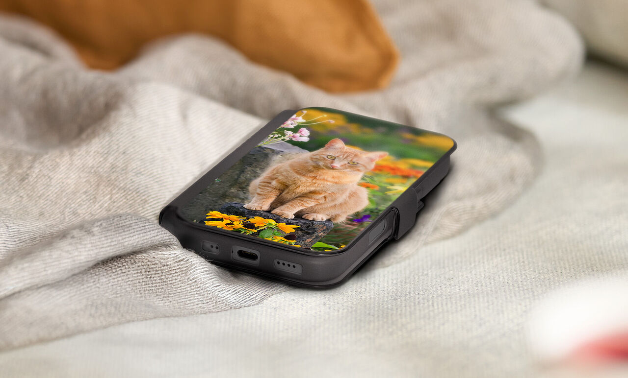 Funda de móvil personalizada con fotos Nivocase con Tapa. Foto de un gato con flores en la carcasa apoyada en una manta en una casa.